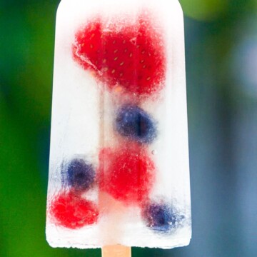 A single coconut water popsicle with strawberries, blueberries, and raspberries.