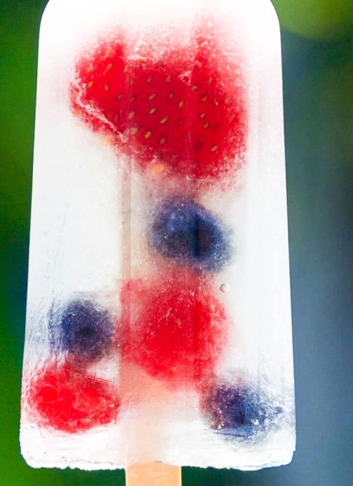 A single coconut water popsicle with strawberries, blueberries, and raspberries.