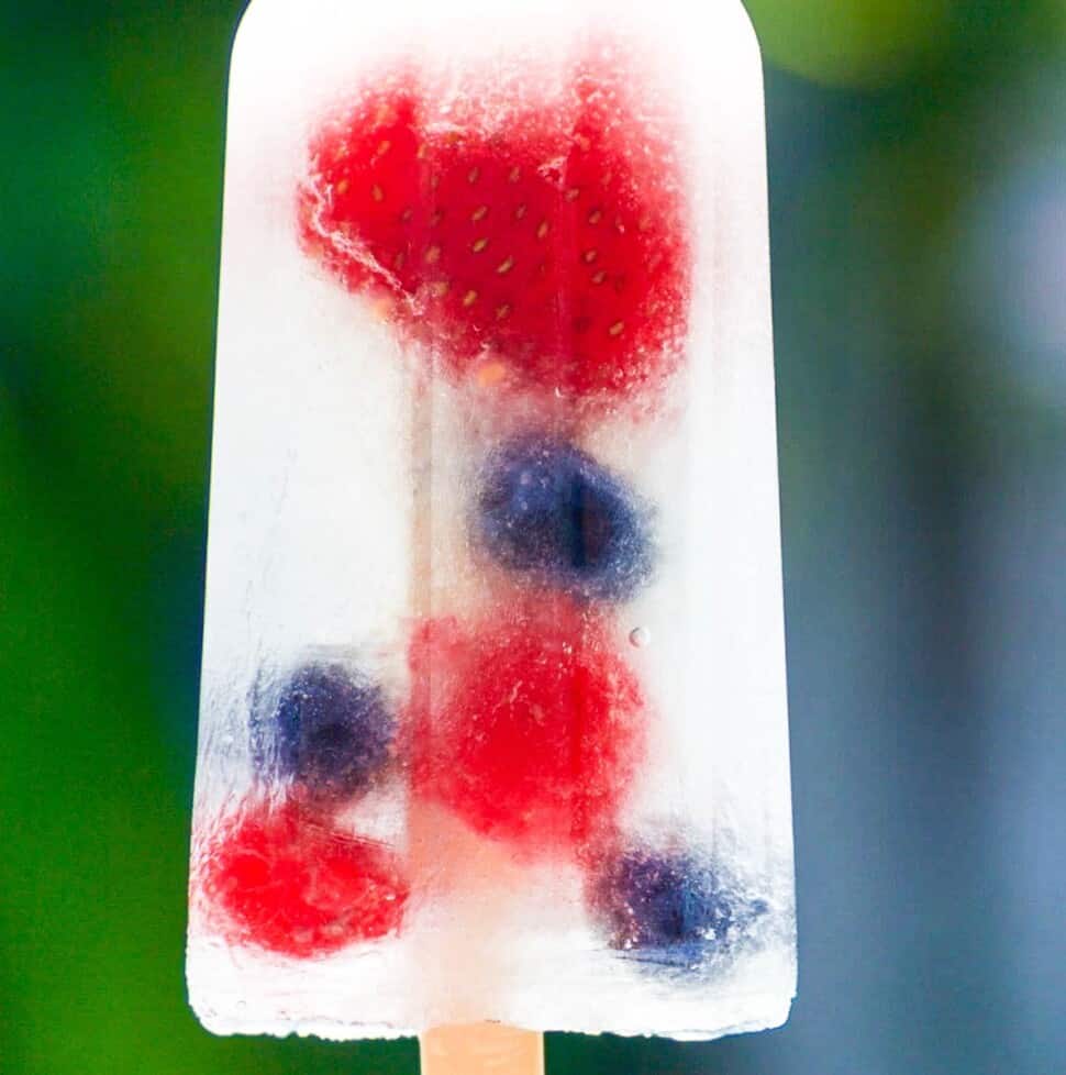 A single coconut water popsicle with strawberries, blueberries, and raspberries.