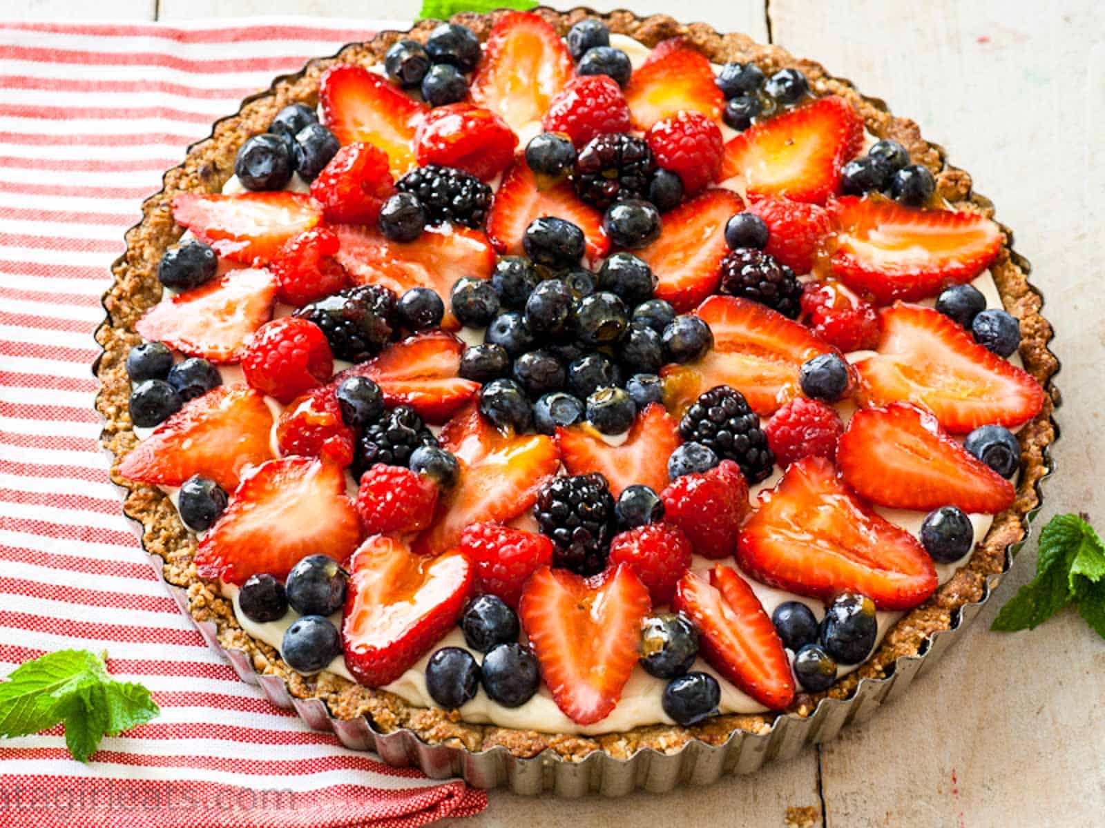 A large fruit tart made with strawberries, blueberries, and raspberries.