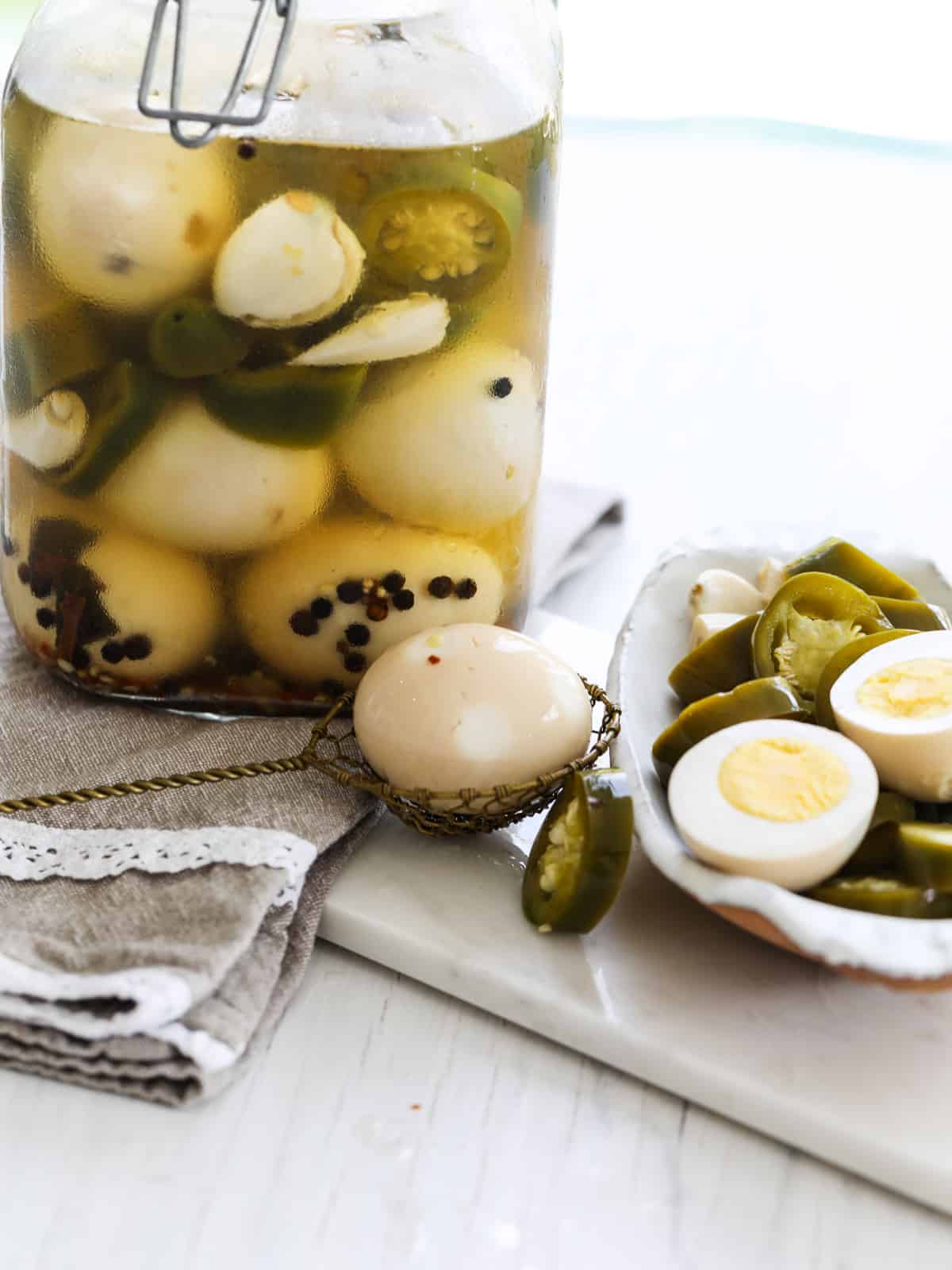 A clear jar filled with pickled eggs and one cut open.