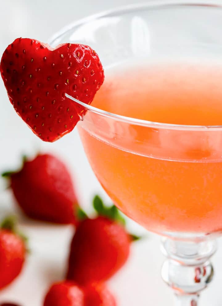 Close up view of strawberry cocktails with heart shaped garnish made from a strawberry on the rim.