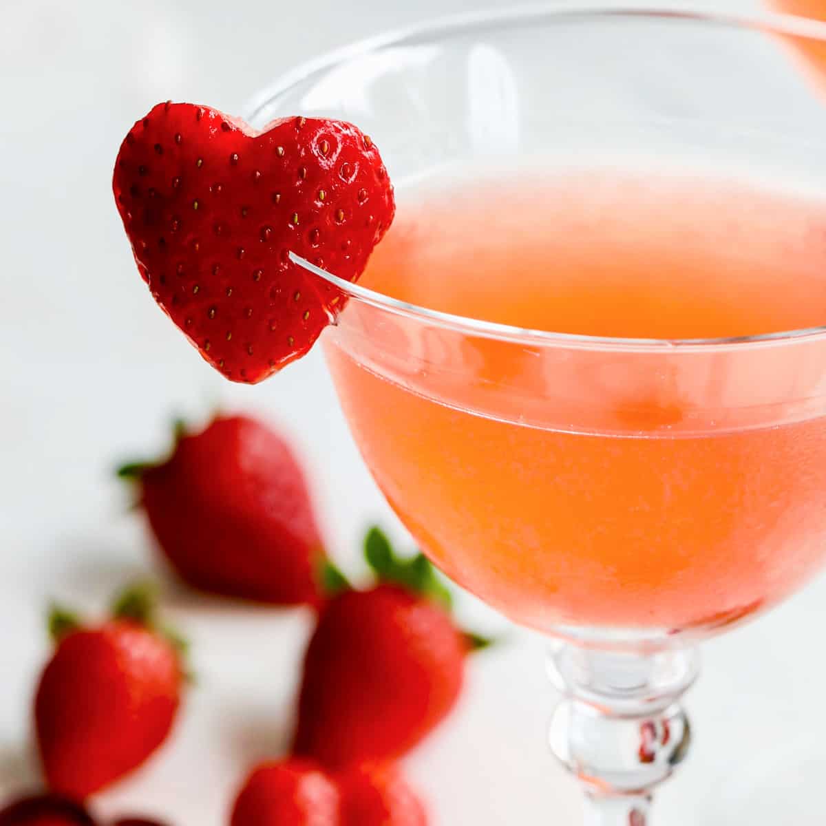 Close up view of strawberry cocktails with heart shaped garnish made from a strawberry on the rim.