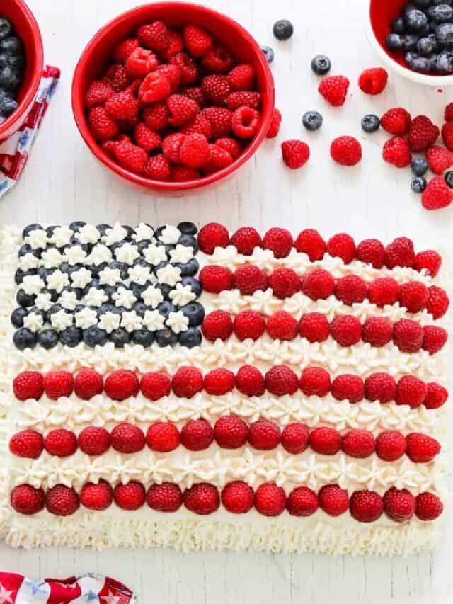 Showing how to decorate an American flag cake with white frosting, raspberries, and blueberries for Fourth of July.