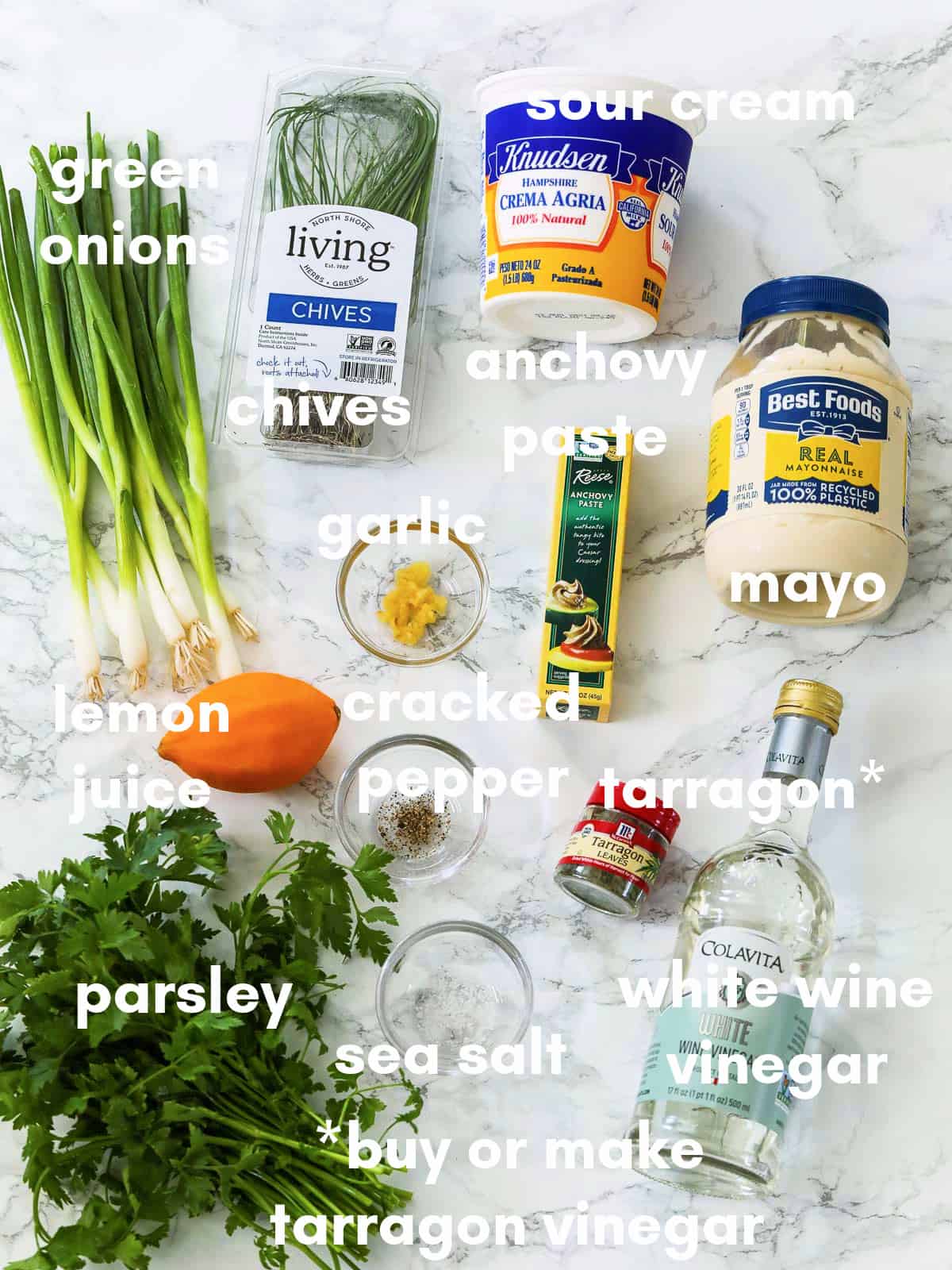 A white table with ingredients to make green goddess dressing all labeled.