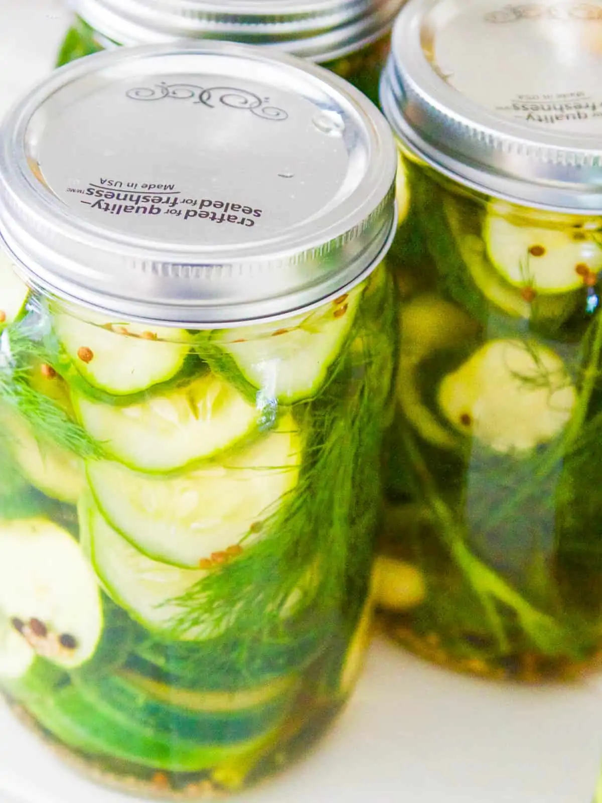 Several jars of homemade pickles on a white table.