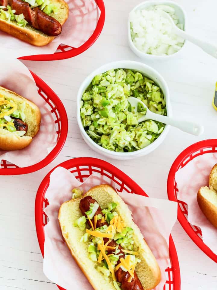 Red food baskets filled with hot dogs and toppings at a cookout party.