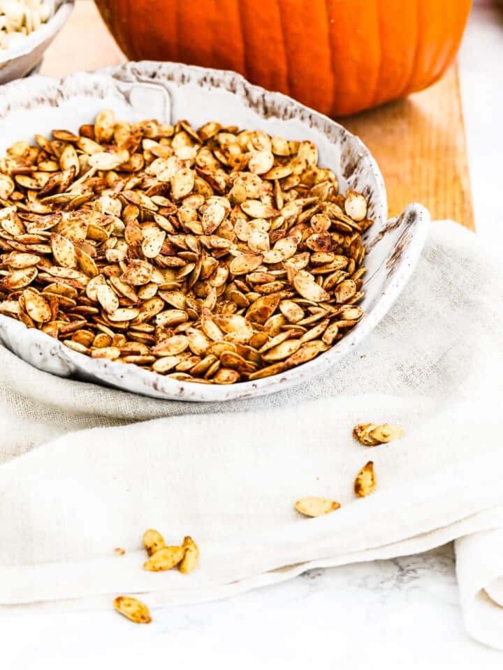 A ceramic bowl showing how roast pumpkin seeds look after taking them out of the oven.