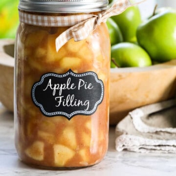 A large jar filled with apple pie filling with a lid and bow.