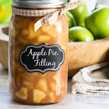 A large jar filled with apple pie filling with a lid and bow.
