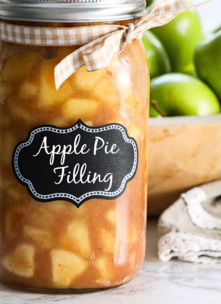 A large jar filled with apple pie filling with a lid and bow.