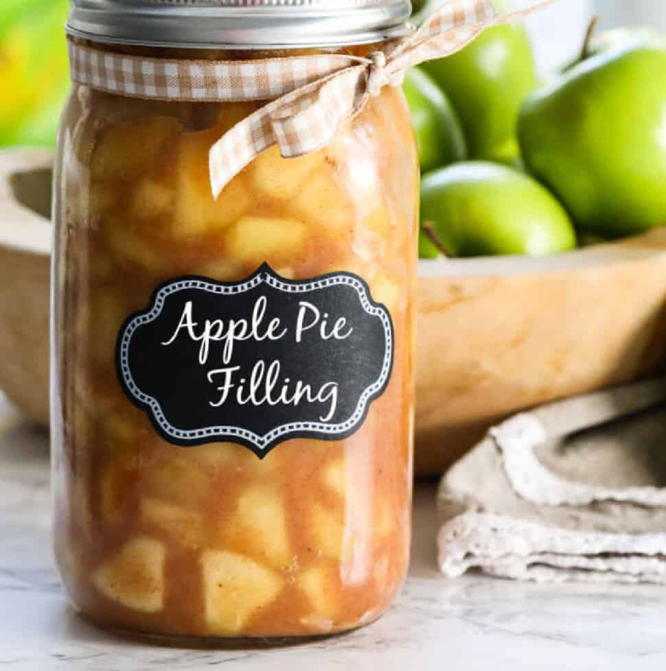 A large jar filled with apple pie filling with a lid and bow.