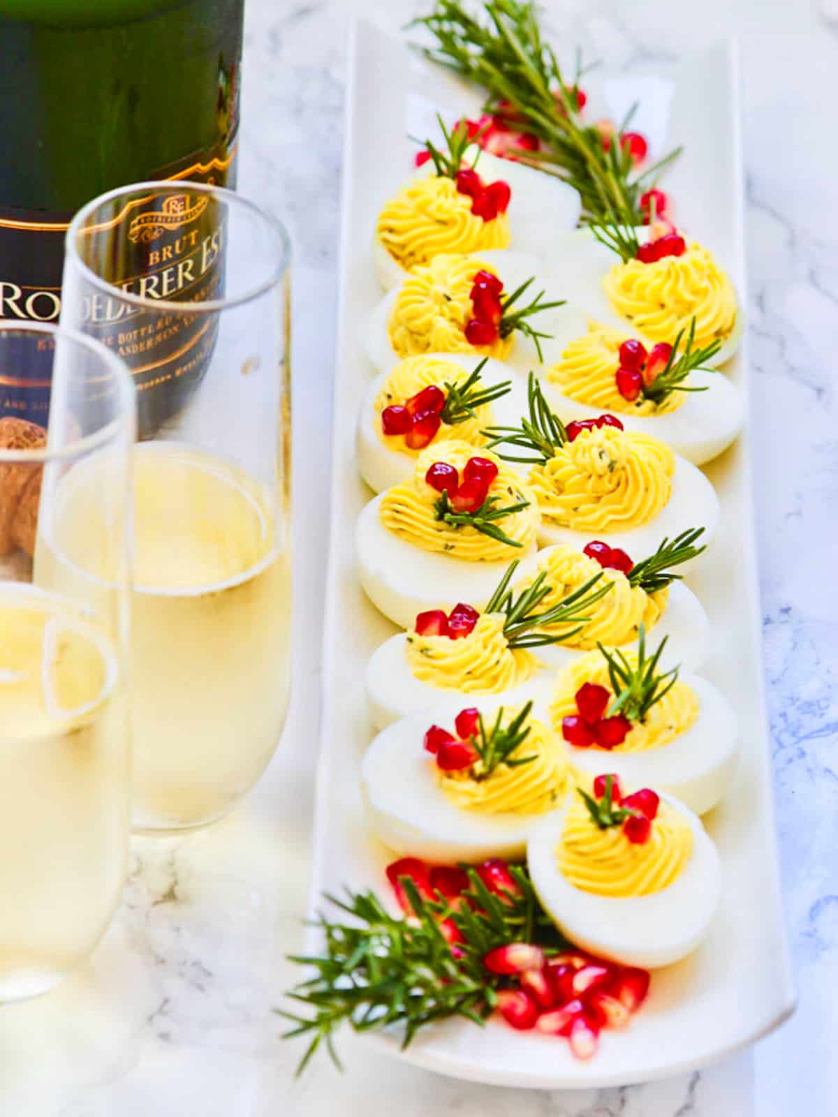 Glasses of champagne with Christmas Deviled Eggs topped with pomegranate seeds.