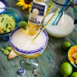 A Cinco de Mayo party with frozen margaritas called Coronaritas, guacamole, and chips on a green table.