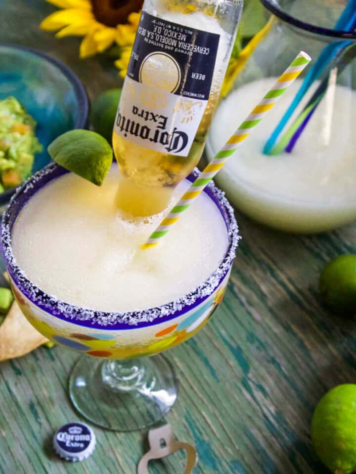 A Cinco de Mayo party with frozen margaritas called Coronaritas, guacamole, and chips on a green table.