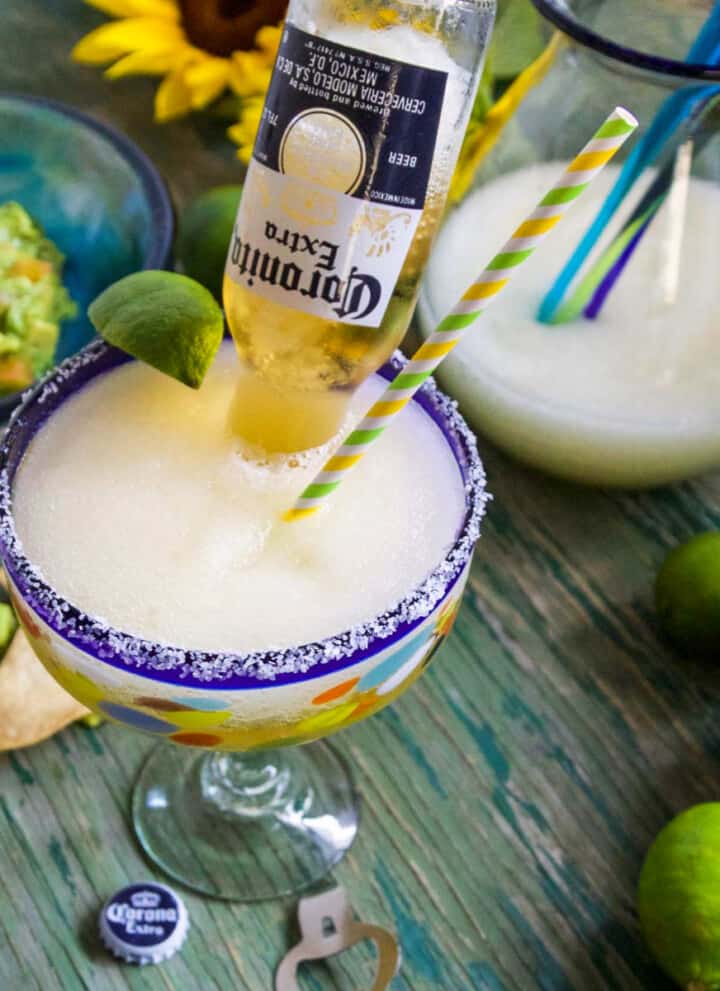 A Cinco de Mayo party with frozen margaritas called Coronaritas, guacamole, and chips on a green table.