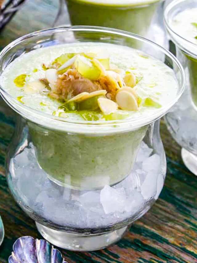 Chilled cucumber soup topped with crab meat and grape garnish served in bowls over ice.