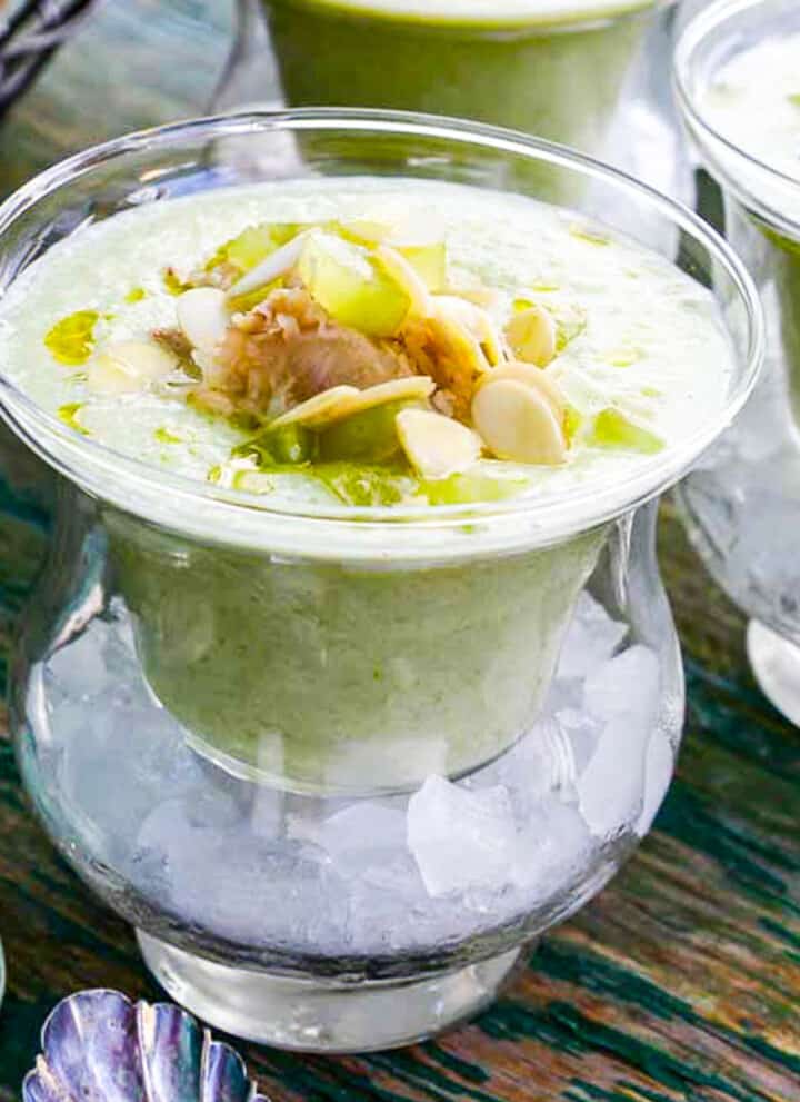 Chilled cucumber soup topped with crab meat and grape garnish served in bowls over ice.