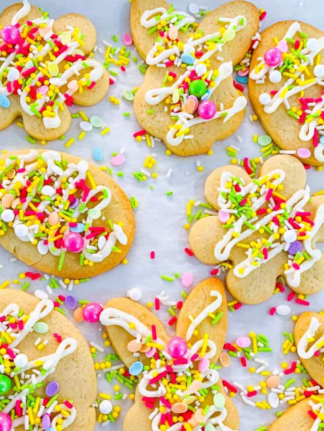 Easter cookies with sprinkles and icing on parchment paper lined cookie tray.