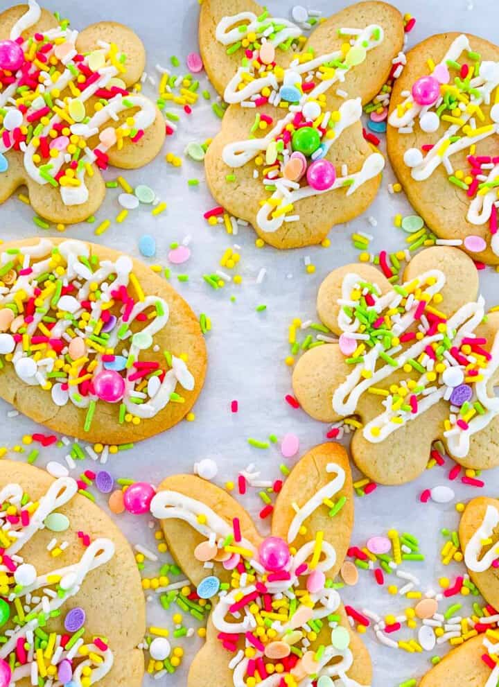 Easter cookies with sprinkles and icing on parchment paper lined cookie tray.