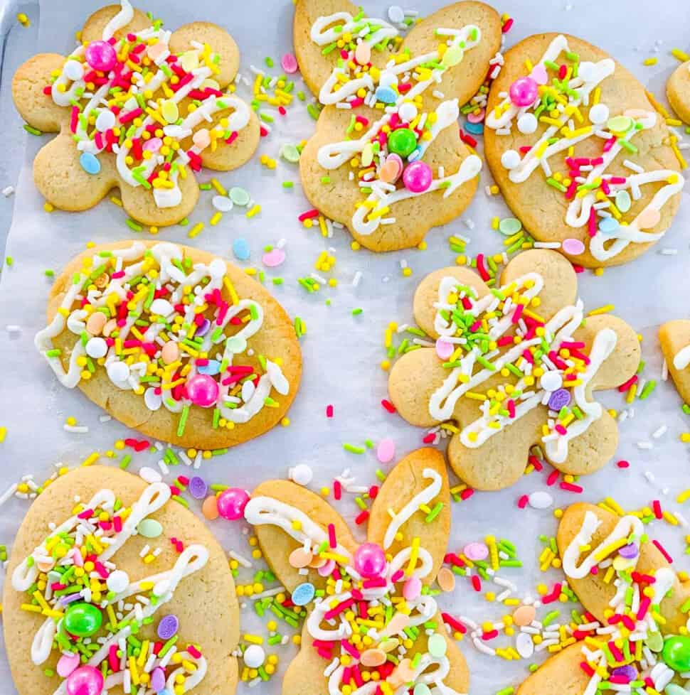 Easter cookies with sprinkles and icing on parchment paper lined cookie tray.