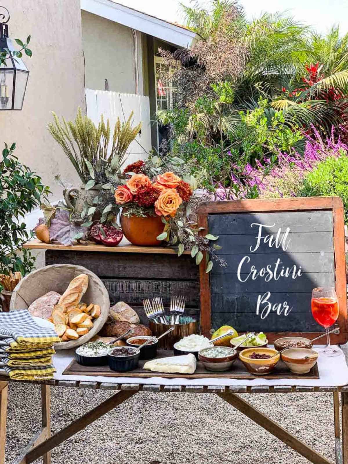 A rustic table with small bowls filled with toppings for a fall appetizer crostini bar.