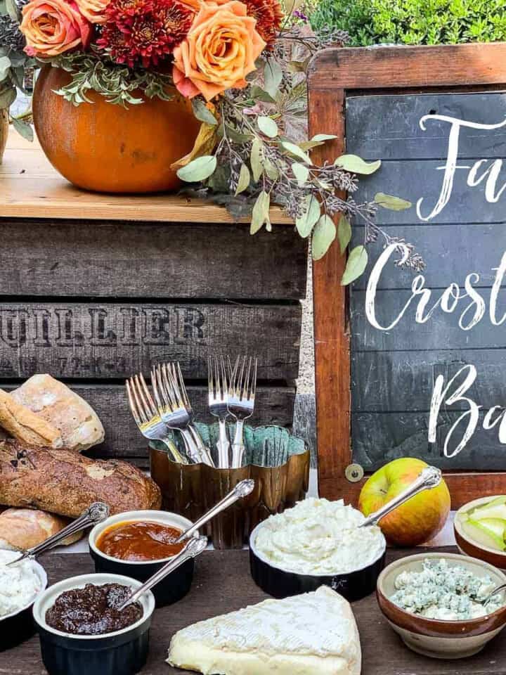 A rustic table with small bowls filled with toppings for a fall appetizer crostini bar.