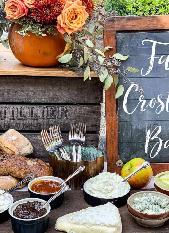 A rustic table with small bowls filled with toppings for a fall appetizer crostini bar.