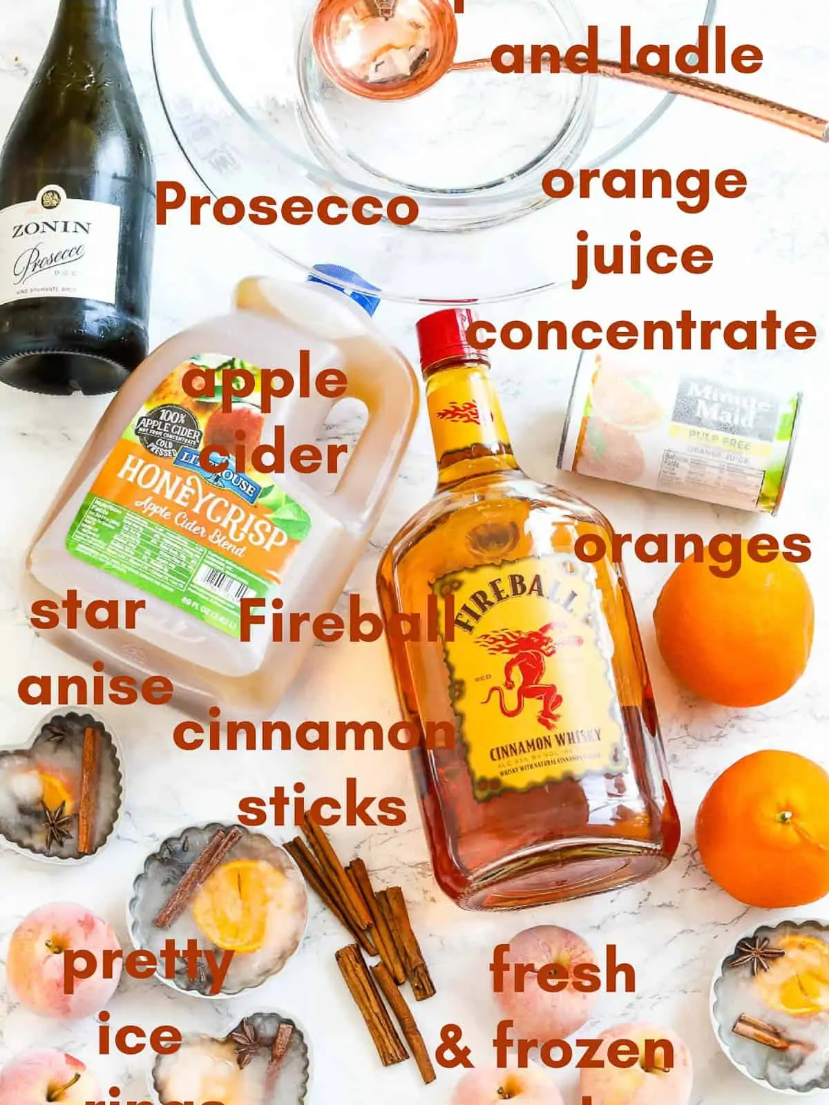 All the ingredients to make Fireball Thanksgiving punch labeled on a table including prosecco and apple cider. 
