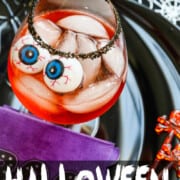 A large glass with black sugar on the rim, ice, and large plastic eyeballs in these Halloween Cocktails.