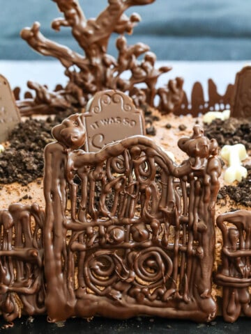 A chocolate Halloween Cake with gate, fence, tree and tombstones.