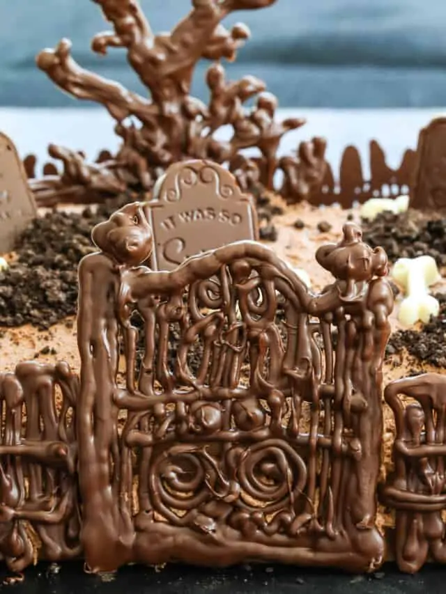 A chocolate Halloween Cake with gate, fence, tree and tombstones.