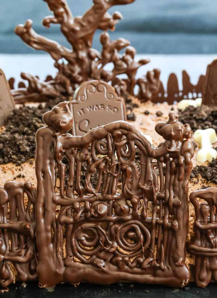 A chocolate Halloween Cake with gate, fence, tree and tombstones.