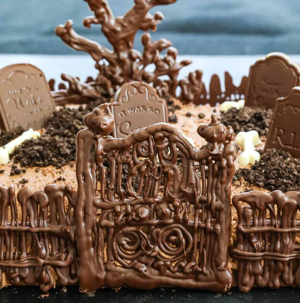 A chocolate Halloween Cake with gate, fence, tree and tombstones.