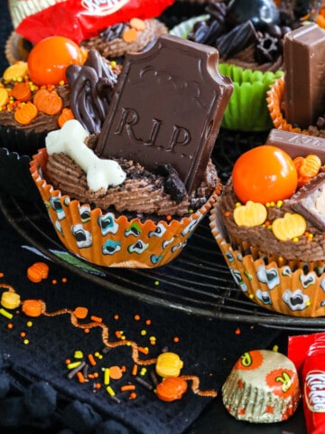 Close up of decorated Halloween cupcake ideas with chocolate frosting, candy, sprinkles on a vintage cooling rack.