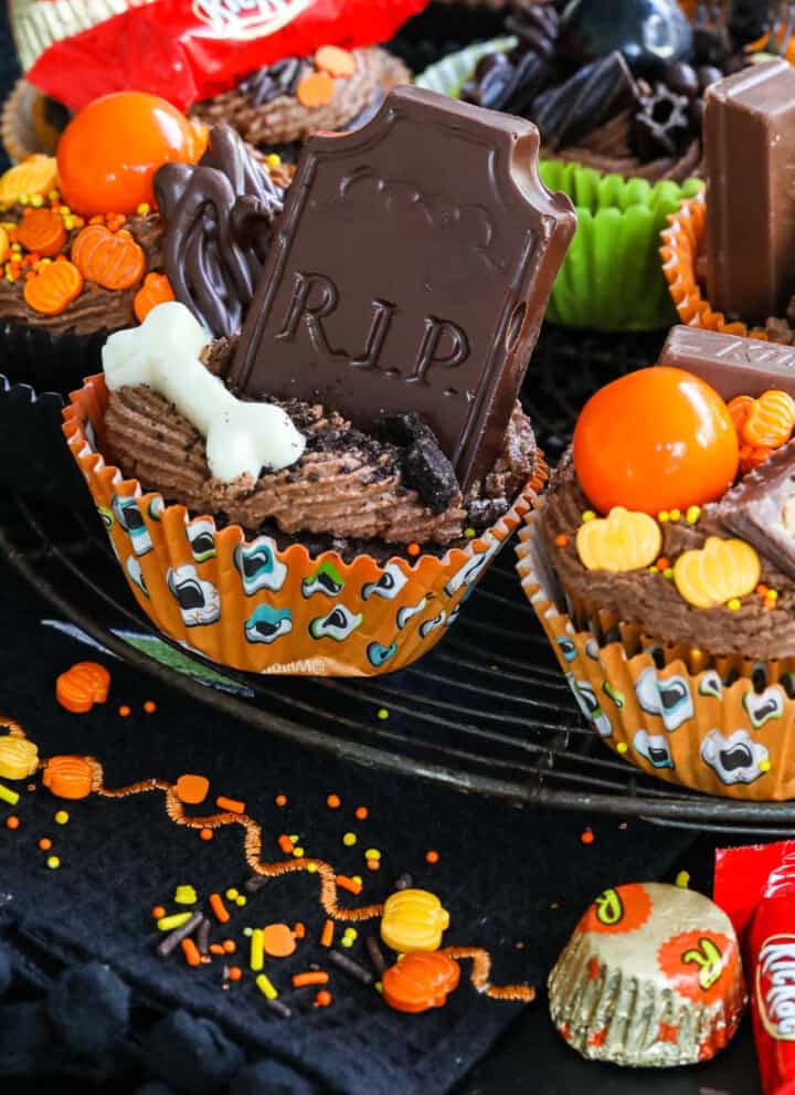 Close up of decorated Halloween cupcake ideas with chocolate frosting, candy, sprinkles on a vintage cooling rack.