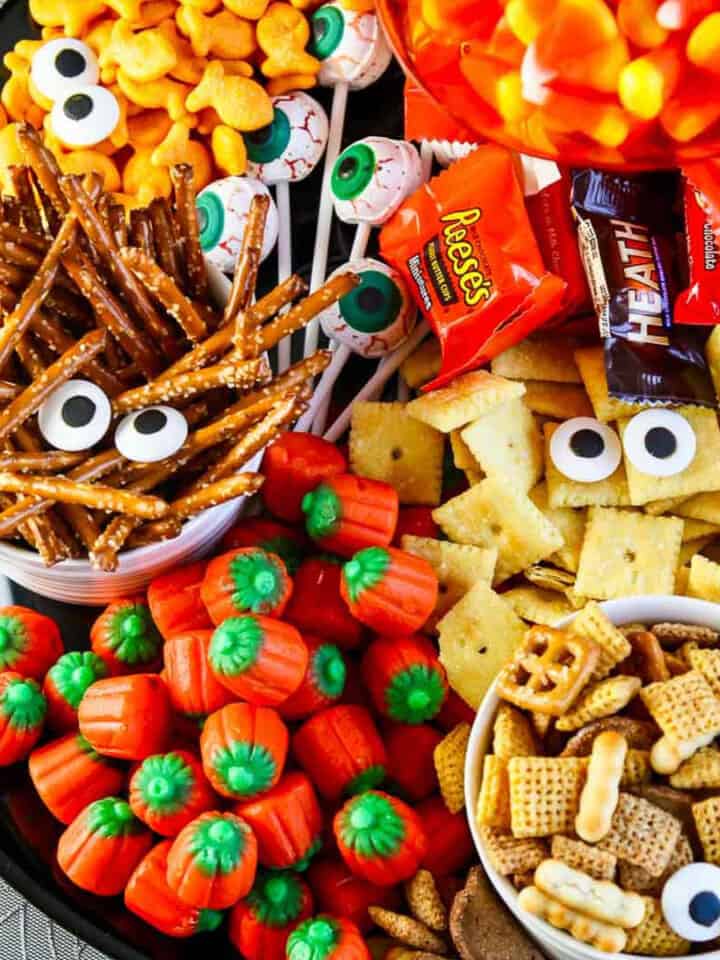 A full platter of Halloween salty snacks and candy decorated with candy eyeballs for an easy last minute Halloween Party Idea.