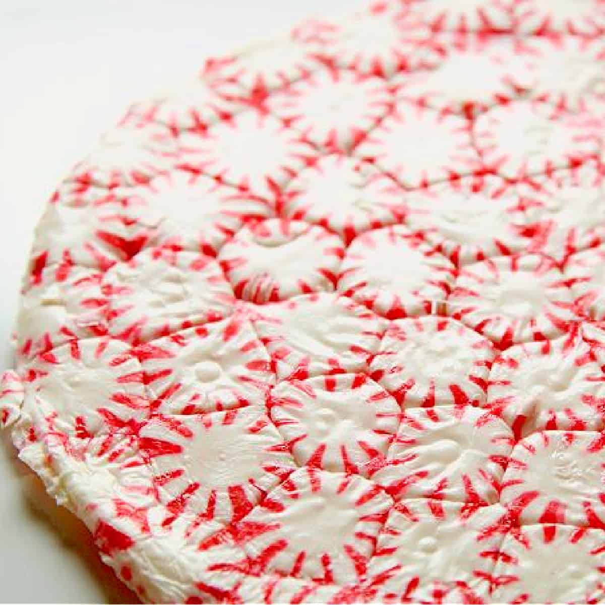 A red and white peppermint candy plate made from melted candy in a round shape.