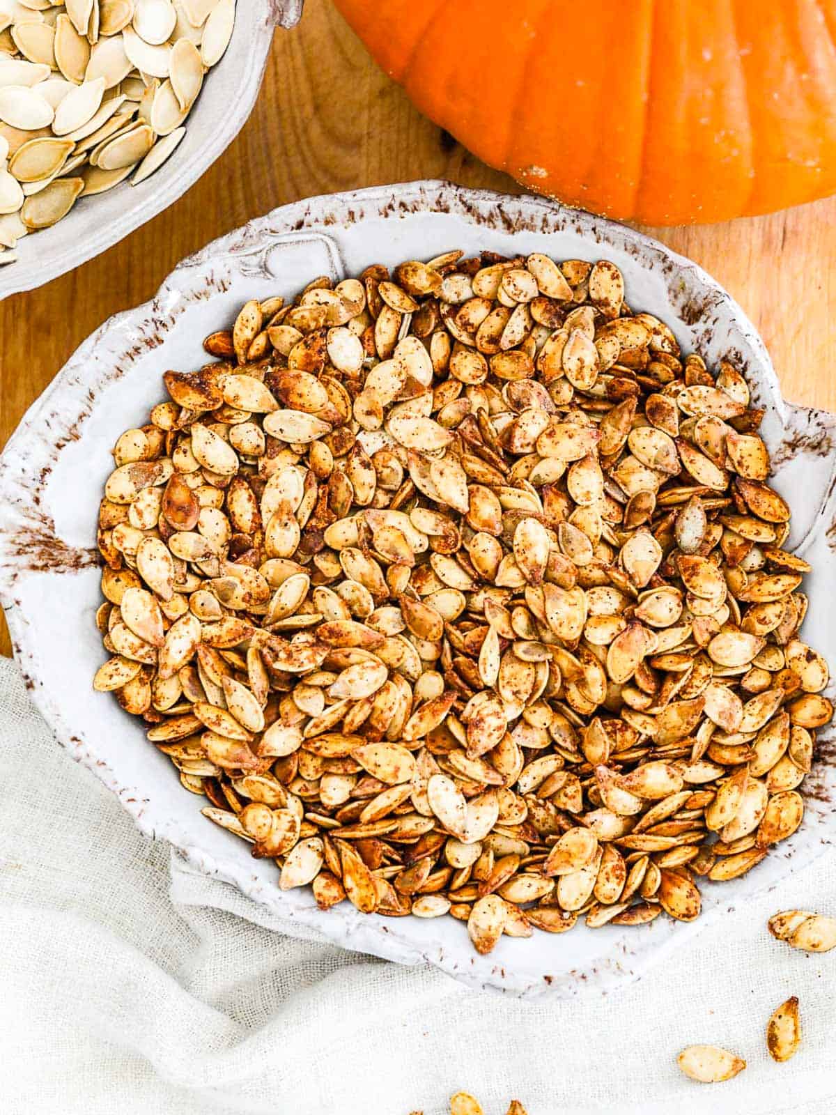 A ceramic bowl filled with seasoned roast pumpkin seeds.