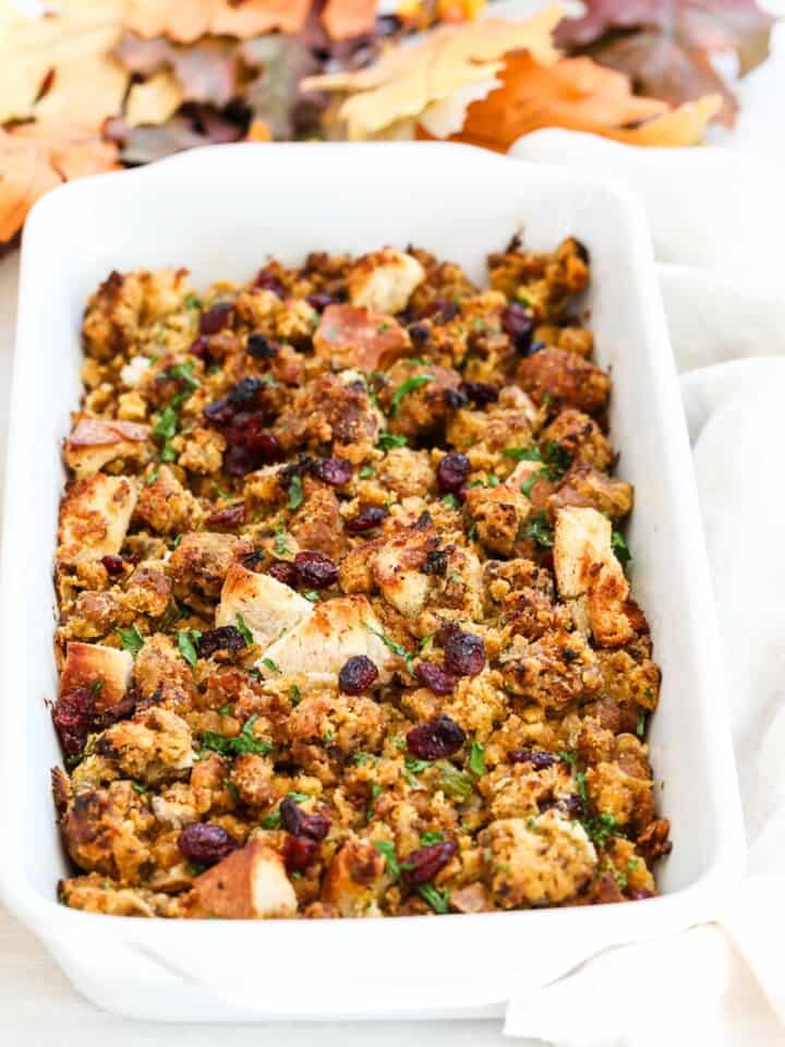 A white casserole dish filled with freshly baked Sausage Stuffing for Thanksgiving.