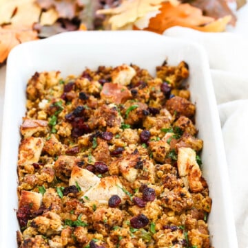A white casserole dish filled with Sausage Stuffing baked to a golden brown.