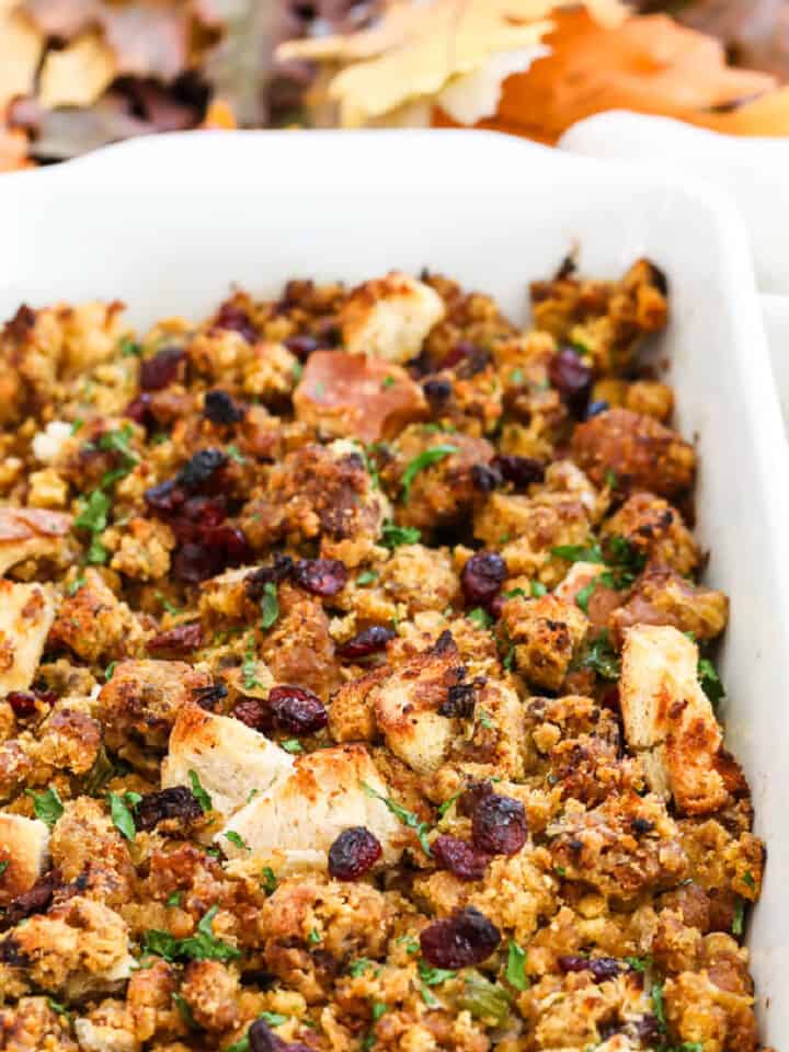A white casserole dish filled with Sausage Stuffing baked to a golden brown.