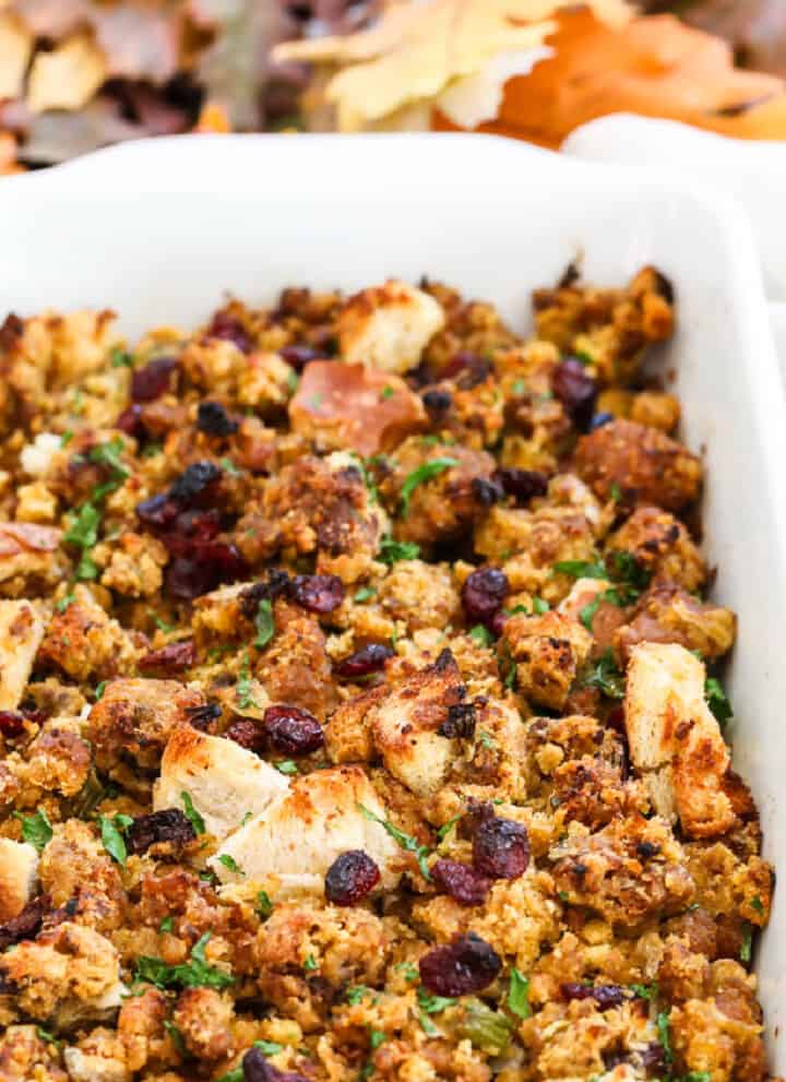 A white casserole dish filled with Sausage Stuffing baked to a golden brown.