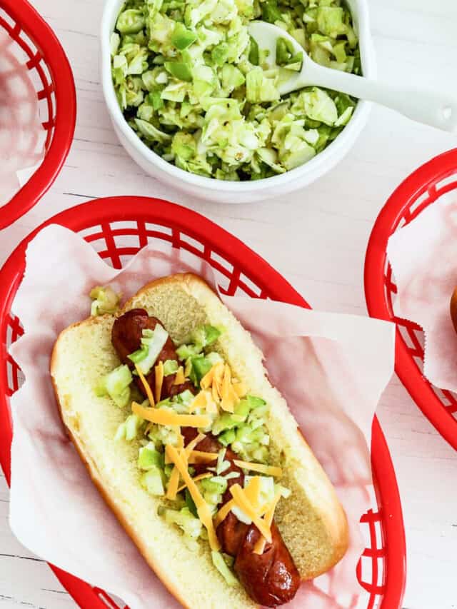 A red plastic food basket lined with paper holding a loaded grilled hot dog.