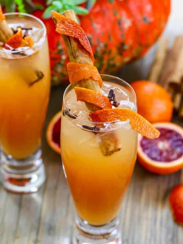 Two glasses of Fireball Cocktails made with Fireball Whisky, garnished with cinnamon sticks and orange rind.