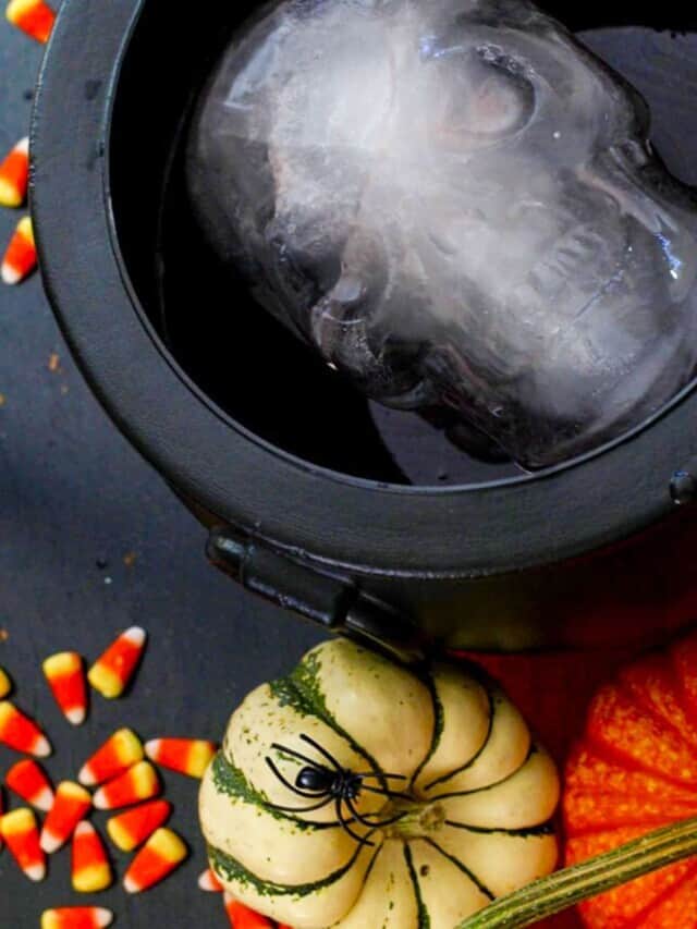 A black witches cauldron filled with Halloween punch and an ice skull peering out.