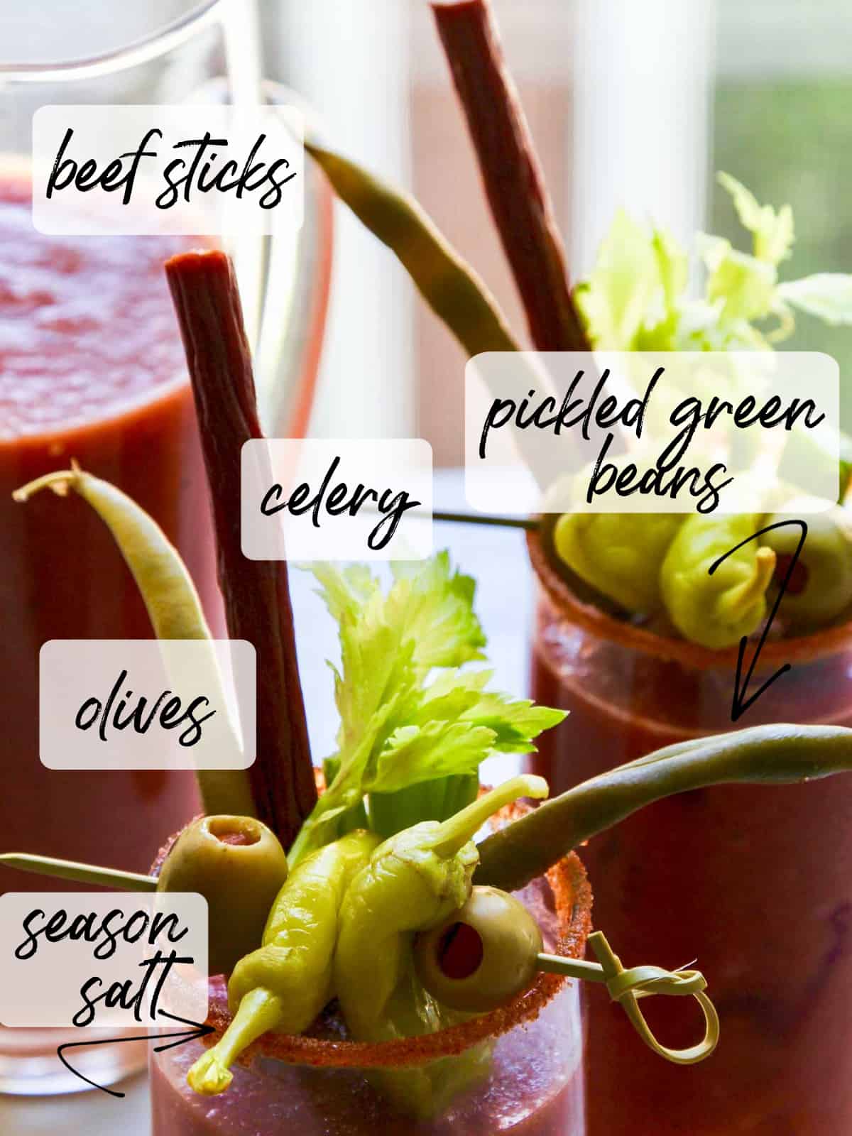 A pitcher of bloody marys with garnish ideas labeled. 
