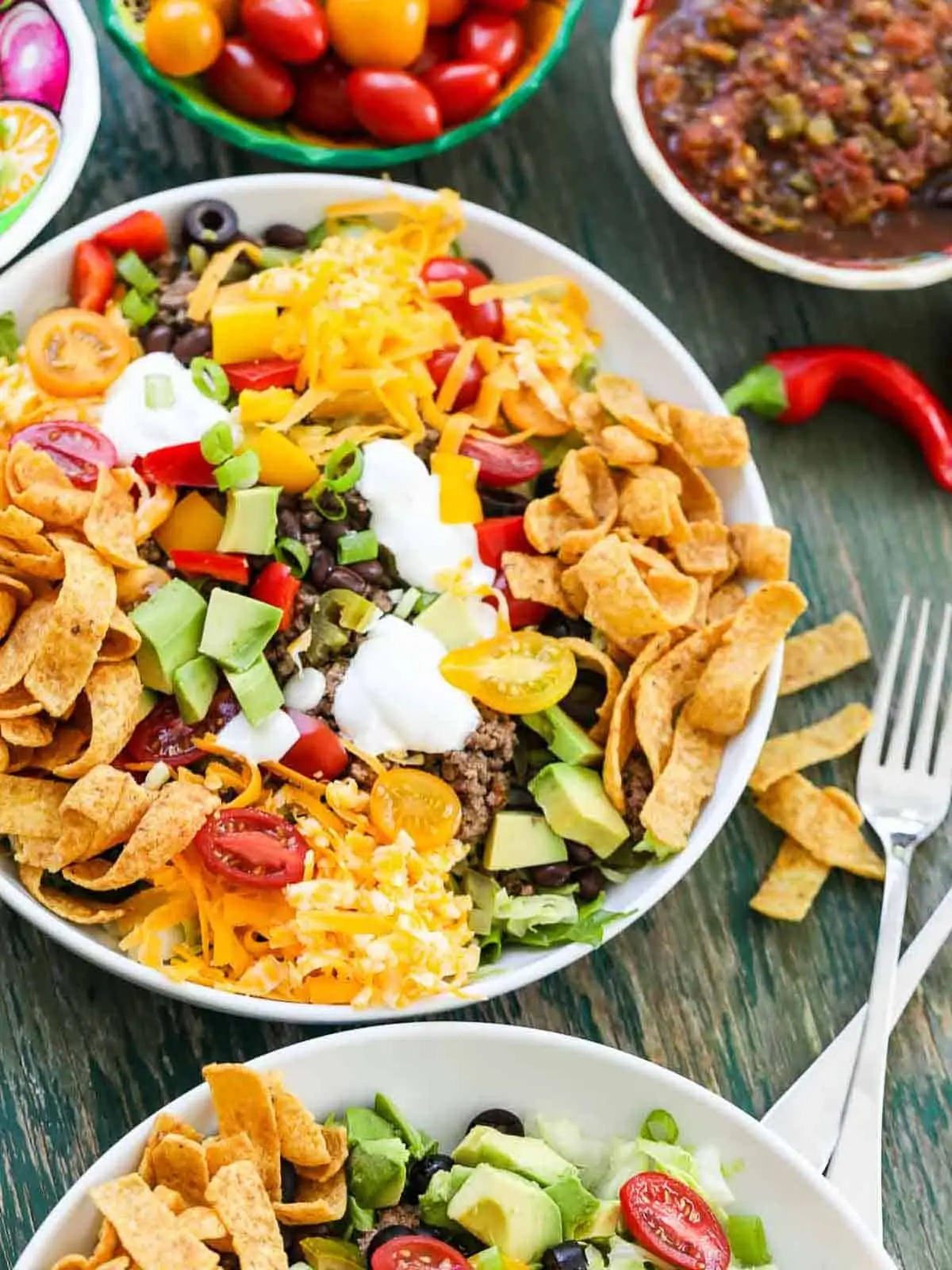 Fritos on top of taco salad with sour cream, avocado, tomatoes, and olives.