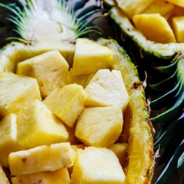 A pineapple bowl filled with fresh cut chunks of pineapple ready to eat.