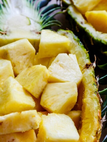 A pineapple bowl filled with fresh cut chunks of pineapple ready to eat.